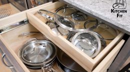 Modern shelf storage with two-level drawers filled with silver pots, pans, and lids.