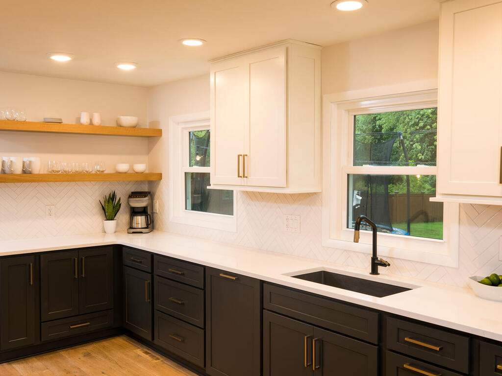 Two-toned kitchen cabinet design with white kitchen cabinets sitting above and modern black cabinets sitting below the white countertop.