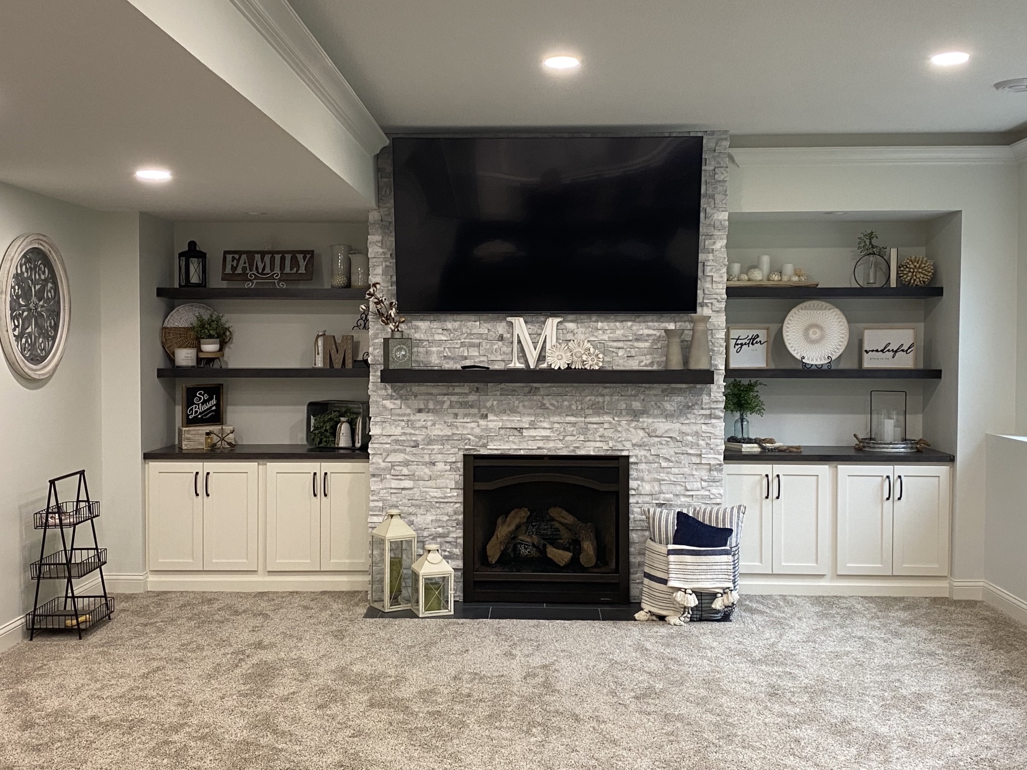 Family Room With Stone Fireplace. Modern white cabinets with black hardware and dark free standing shelves.